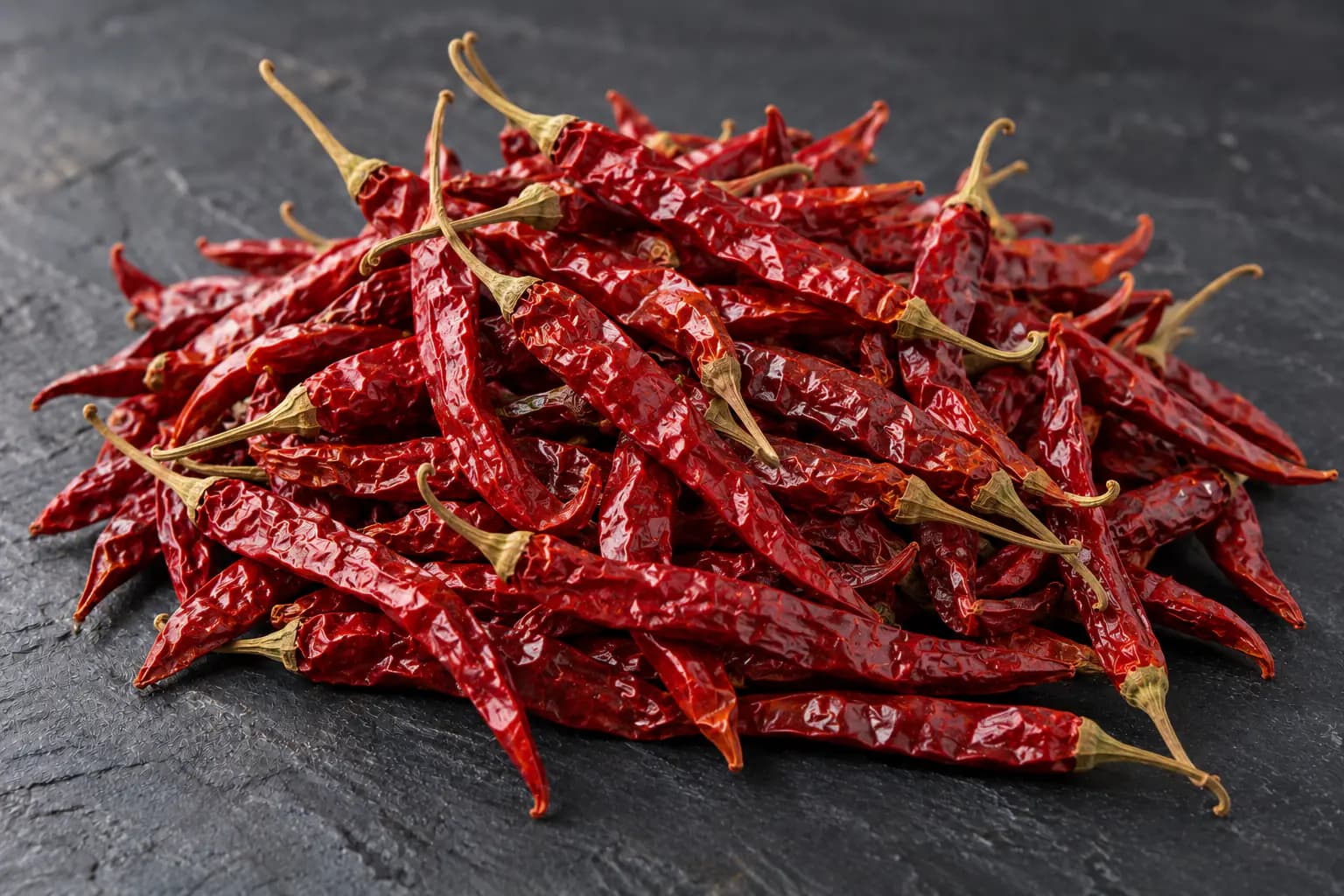 Heap of long dried red chillies on slate